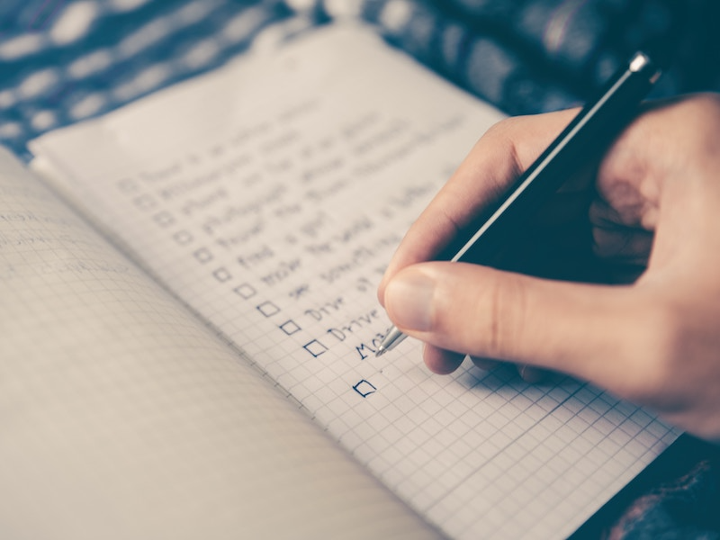 Hand holding a pen and writing notes on a notepad.